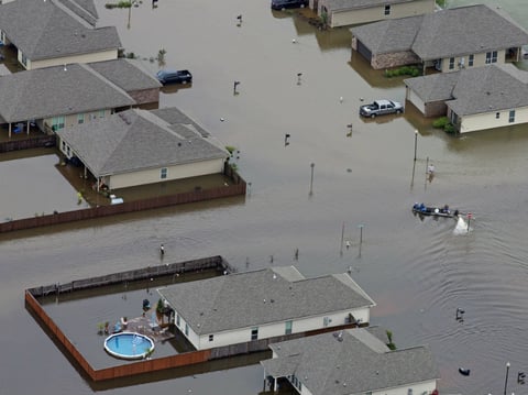 In this aerial photo a boat motors between flooded homes on Saturday after heavy rains in the region in Hammond, La.
